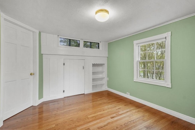 3 Norman Ave, Newburyport, MA 01950 - unfurnished bedroom with a textured ceiling, baseboards, light wood finished floors, crown molding, and a closet