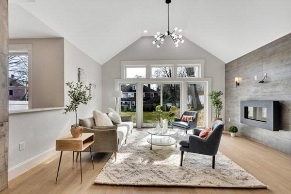 living room featuring a large fireplace, vaulted ceiling, light hardwood / wood-style flooring, and a notable chandelier