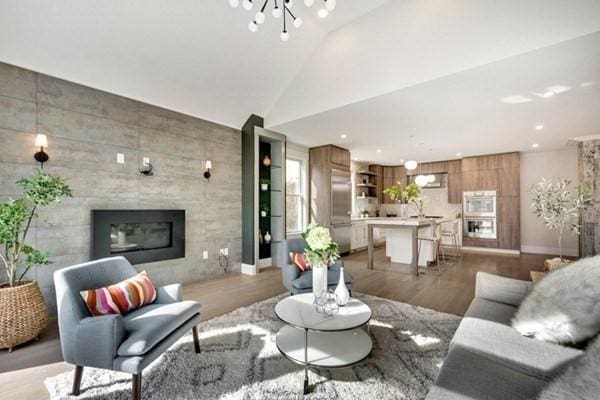 living room featuring sink, a chandelier, vaulted ceiling, a tile fireplace, and light hardwood / wood-style floors