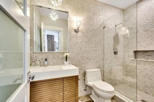 bathroom featuring vanity, toilet, a chandelier, and a tile shower