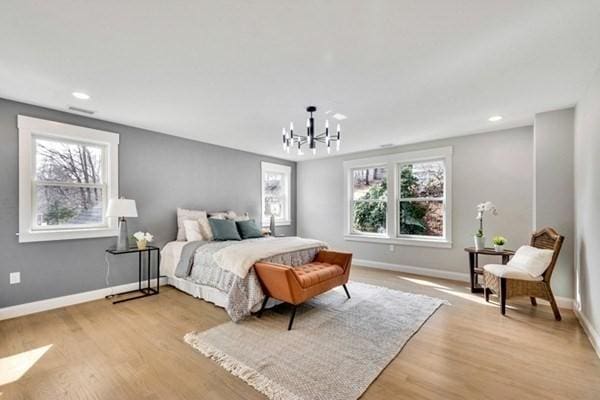 bedroom featuring a chandelier, multiple windows, and light hardwood / wood-style flooring