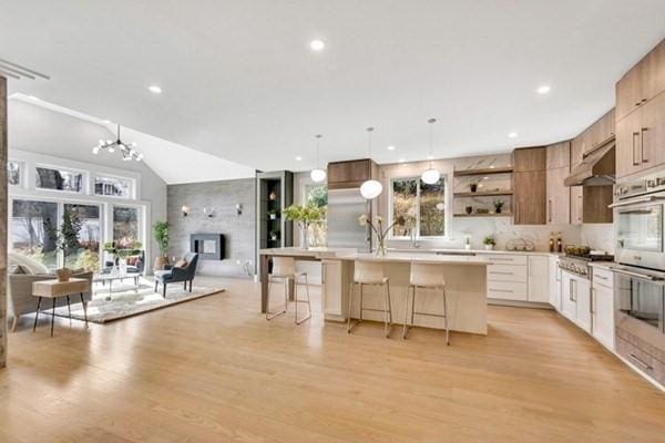 kitchen featuring light hardwood / wood-style floors, an island with sink, white cabinets, and a kitchen bar