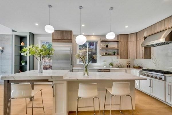 kitchen featuring tasteful backsplash, a breakfast bar area, white cabinets, a center island, and stainless steel appliances