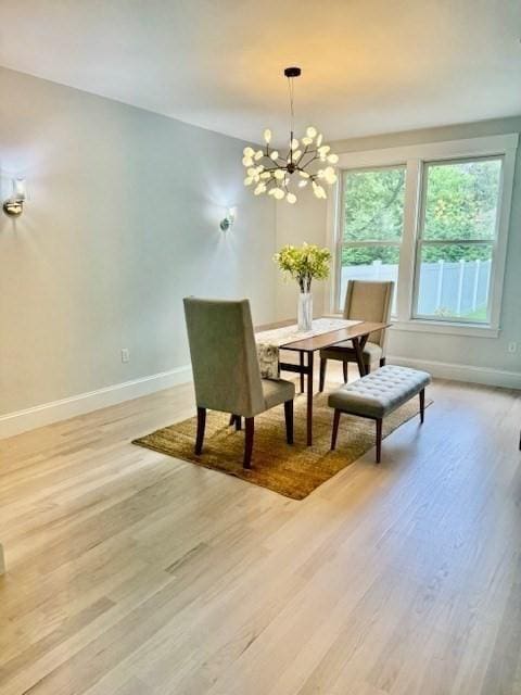 dining area with light hardwood / wood-style flooring and a notable chandelier