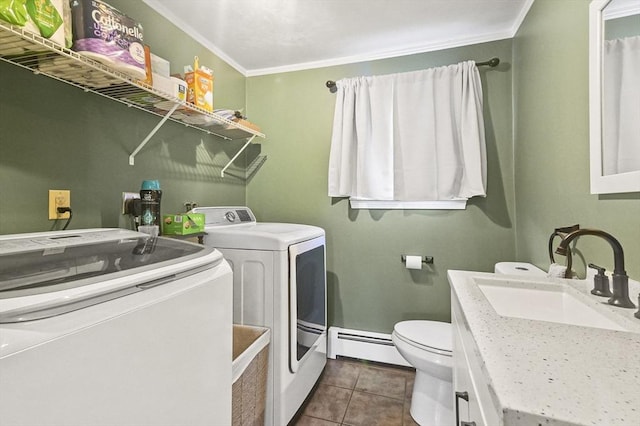 clothes washing area with ornamental molding, dark tile patterned floors, baseboard heating, sink, and washing machine and clothes dryer