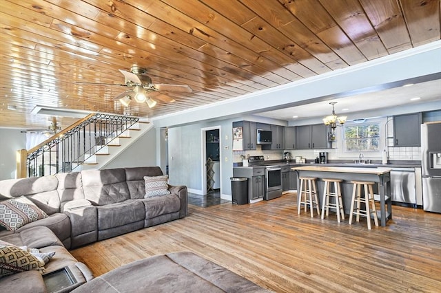 living room featuring sink, crown molding, wood ceiling, ceiling fan with notable chandelier, and light wood-type flooring