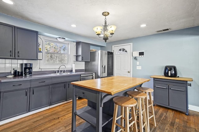 kitchen with dark hardwood / wood-style flooring, stainless steel appliances, sink, an inviting chandelier, and gray cabinets