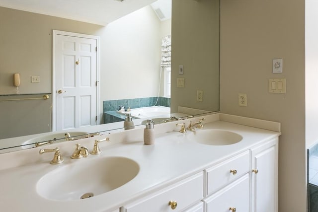 bathroom with double vanity, a sink, and a bath