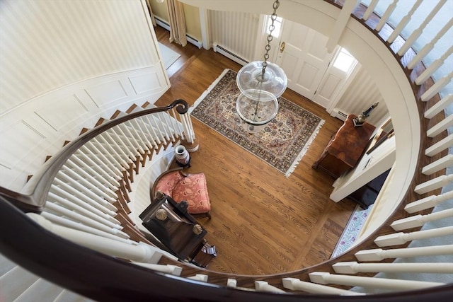 living area with stairs, a baseboard radiator, arched walkways, and wood finished floors