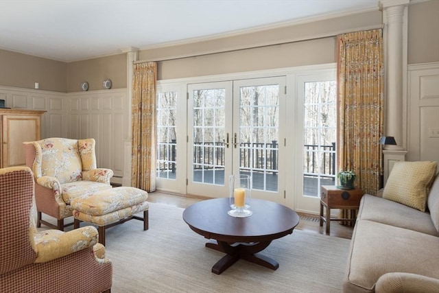 living area featuring ornamental molding, light wood-type flooring, french doors, and plenty of natural light