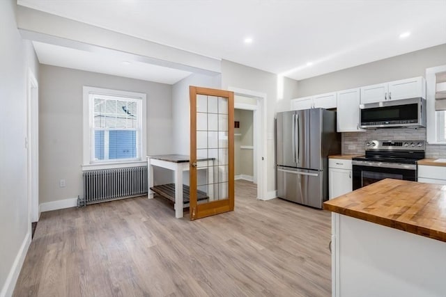 kitchen featuring white cabinets, appliances with stainless steel finishes, radiator, wood counters, and decorative backsplash