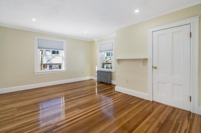 spare room with hardwood / wood-style flooring, radiator heating unit, ornamental molding, and a wealth of natural light