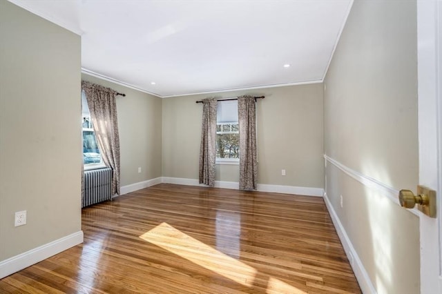 spare room with plenty of natural light, hardwood / wood-style floors, radiator heating unit, and ornamental molding