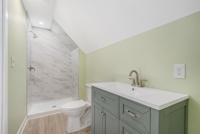 bathroom with vanity, toilet, tiled shower, and wood-type flooring