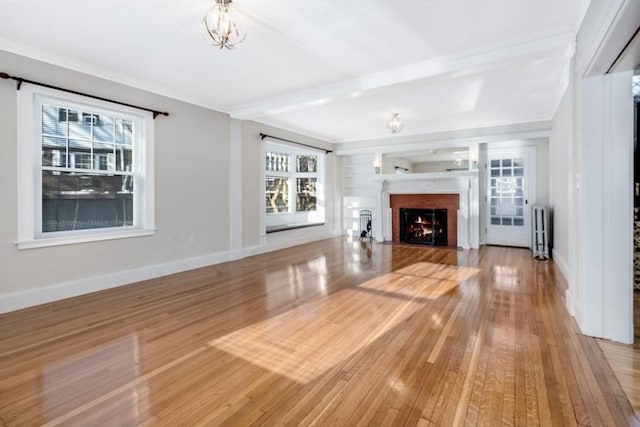 unfurnished living room featuring light hardwood / wood-style floors, radiator, ornamental molding, and an inviting chandelier