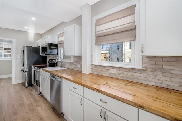 kitchen with light hardwood / wood-style flooring, wooden counters, tasteful backsplash, white cabinetry, and stainless steel appliances