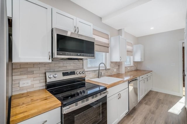 kitchen with white cabinets, wood counters, appliances with stainless steel finishes, and sink