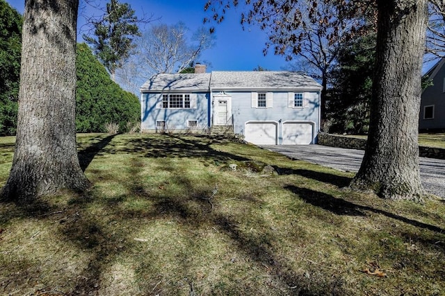 view of front of property with a garage, a chimney, and a front yard