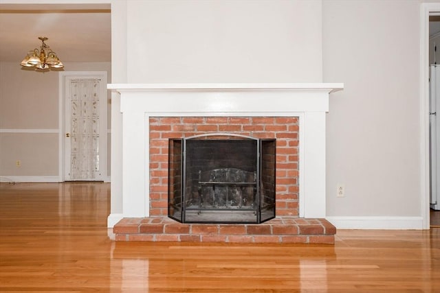 details featuring baseboards, a brick fireplace, and wood finished floors