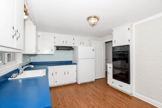 kitchen with light wood-type flooring, freestanding refrigerator, white cabinets, dobule oven black, and a sink