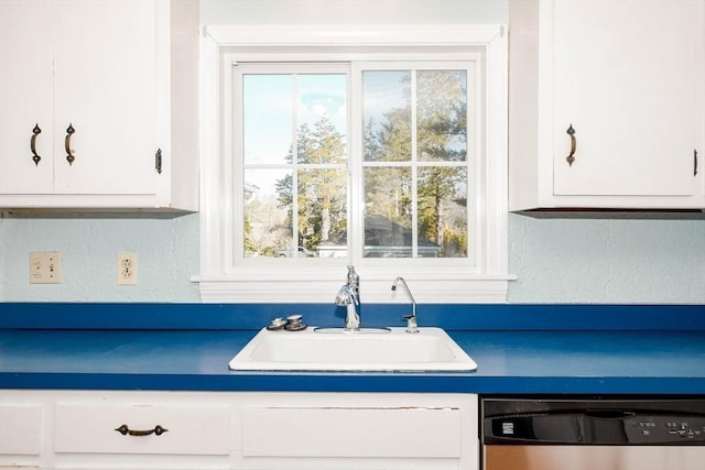 kitchen featuring a sink, dark countertops, white cabinets, dishwasher, and a textured wall