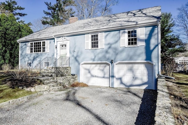 view of front of house featuring aphalt driveway, an attached garage, a chimney, and roof with shingles