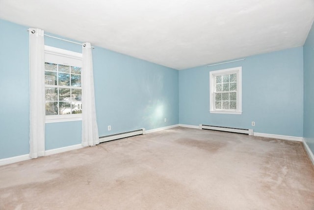 carpeted spare room featuring a baseboard heating unit, plenty of natural light, and baseboards