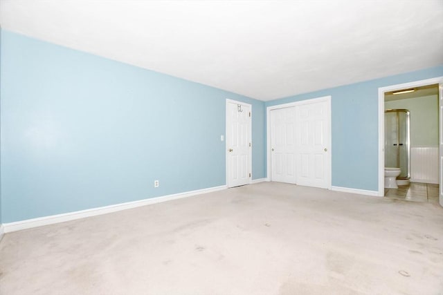 unfurnished bedroom featuring a closet, baseboards, carpet, and ensuite bathroom