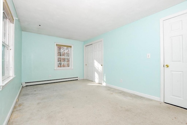 spare room featuring baseboard heating, baseboards, and carpet