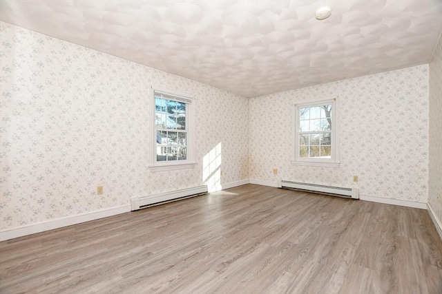 empty room with baseboard heating, wallpapered walls, and a baseboard heating unit