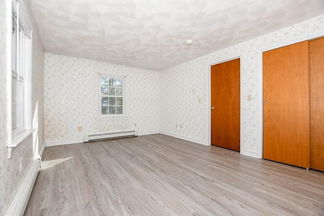 empty room with a baseboard radiator, wood finished floors, and wallpapered walls