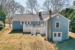 rear view of property featuring a lawn, a chimney, and a deck