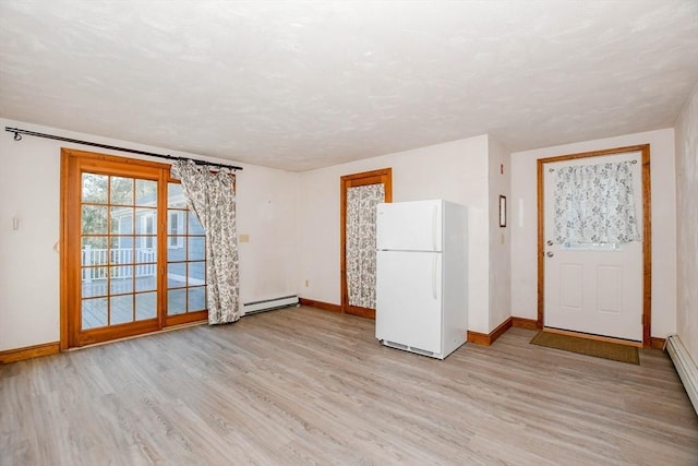 unfurnished room with a baseboard radiator, baseboards, and light wood-style floors