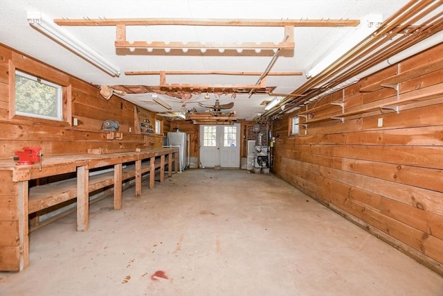 basement featuring freestanding refrigerator, a workshop area, and wood walls