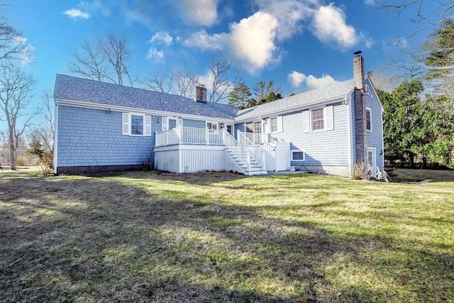 rear view of property featuring a shingled roof, stairs, a lawn, a chimney, and a deck