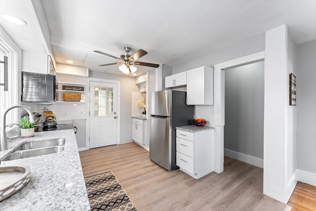 kitchen featuring white cabinetry, stainless steel fridge, sink, and decorative backsplash