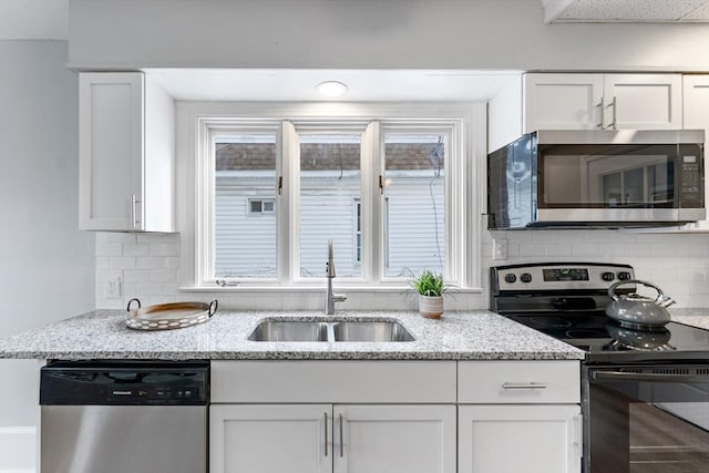 kitchen with stainless steel appliances, sink, white cabinets, and light stone counters