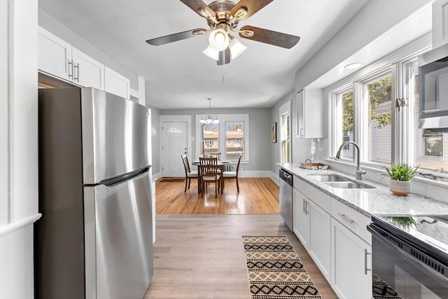 kitchen with light stone countertops, appliances with stainless steel finishes, sink, and white cabinets