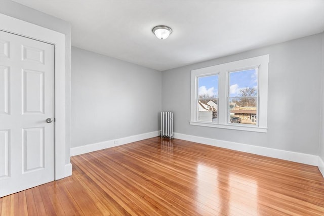 empty room with radiator heating unit and light hardwood / wood-style flooring