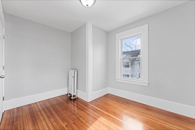 unfurnished room featuring hardwood / wood-style floors and radiator heating unit