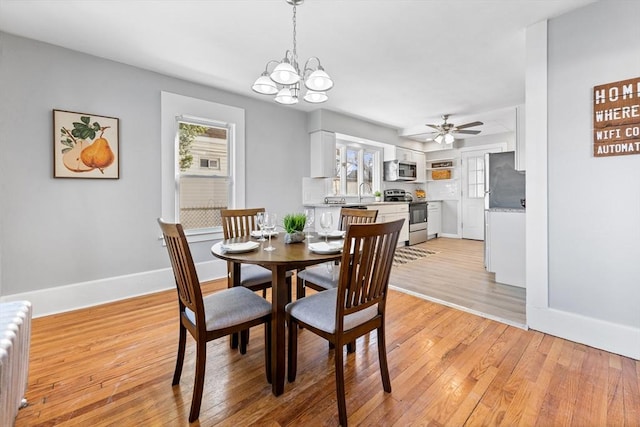 dining room with sink, ceiling fan with notable chandelier, radiator heating unit, and light hardwood / wood-style floors