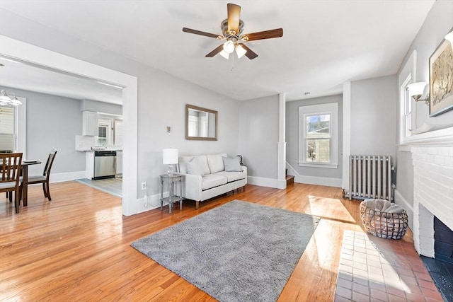 living room with radiator, a fireplace, hardwood / wood-style floors, and ceiling fan