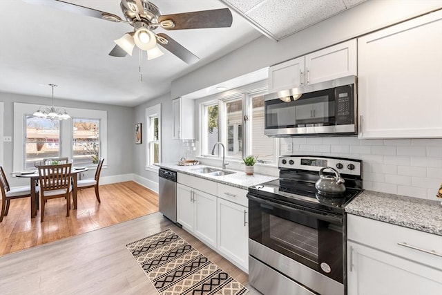 kitchen with white cabinetry, sink, stainless steel appliances, and light stone countertops