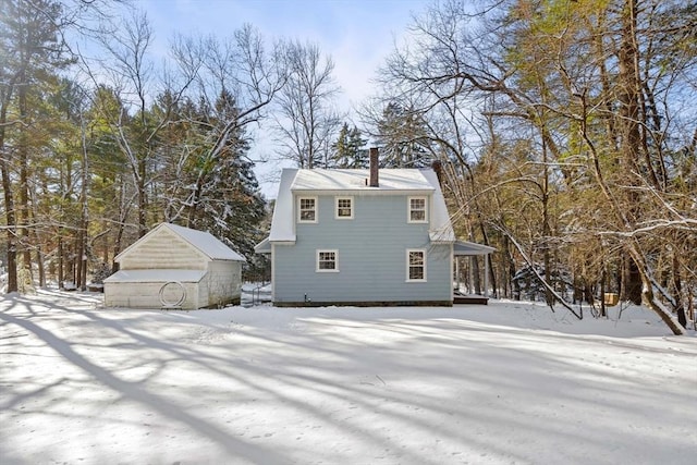 snow covered rear of property with an outbuilding and a garage