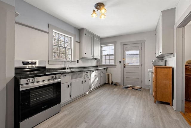 kitchen with stainless steel range with electric cooktop, a wealth of natural light, sink, and radiator heating unit