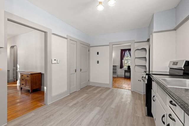 kitchen featuring electric stove, white cabinets, and light wood-type flooring