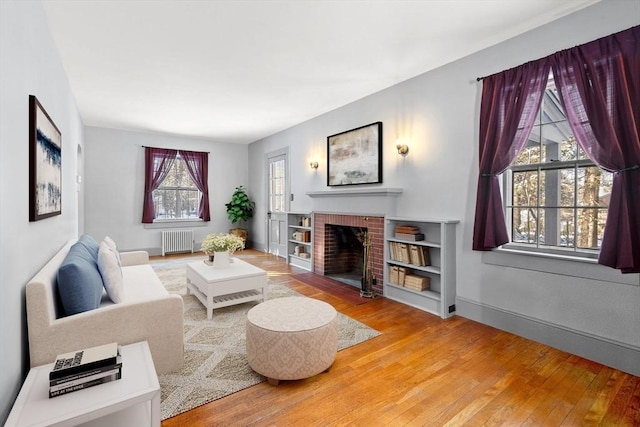 living room featuring wood-type flooring, a fireplace, and radiator heating unit