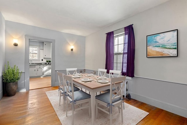 dining space featuring light wood-type flooring, a wealth of natural light, and sink