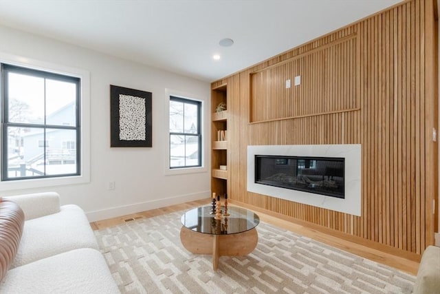 living room with light wood-type flooring and built in shelves