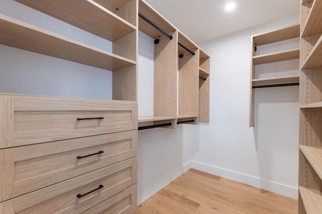 walk in closet with light hardwood / wood-style floors